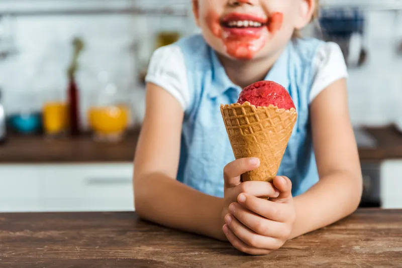 cropped shot of adorable happy child holding delicious ice cream cone