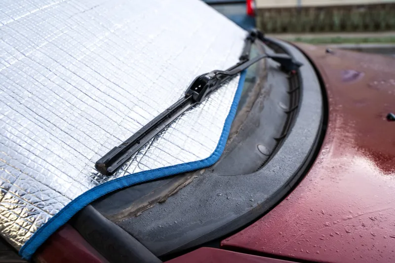 frosted windshield of a red car on a winter morning ice has to be scraped away if someone would like to drive a protective mat does protect against to frost on the windshield