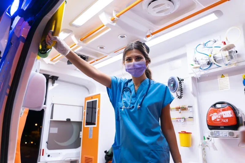 portrait of young female paramedic with face mask working in an ambulance during pandemic