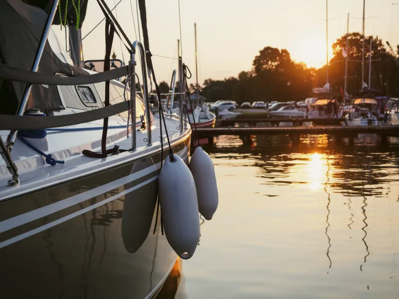 sunset view on sailing yacht moored on jetty in the port, close up view on sailboat hull, bow and fenders
