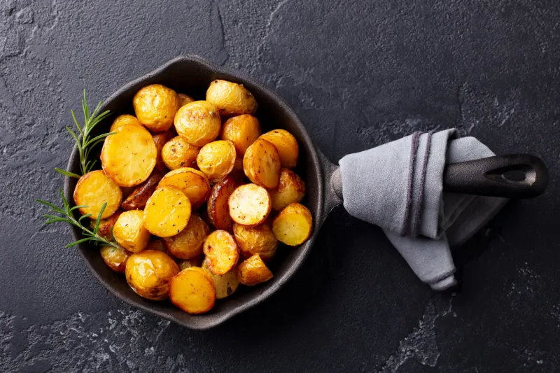 roasted baby potatoes in iron skillet dark grey background top view