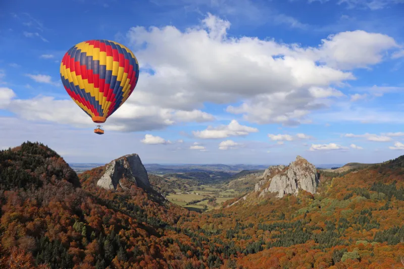 hot air balloon flying over ancient volcanos area tuiliere and sanadoire rocks monts dore, auvergne, france