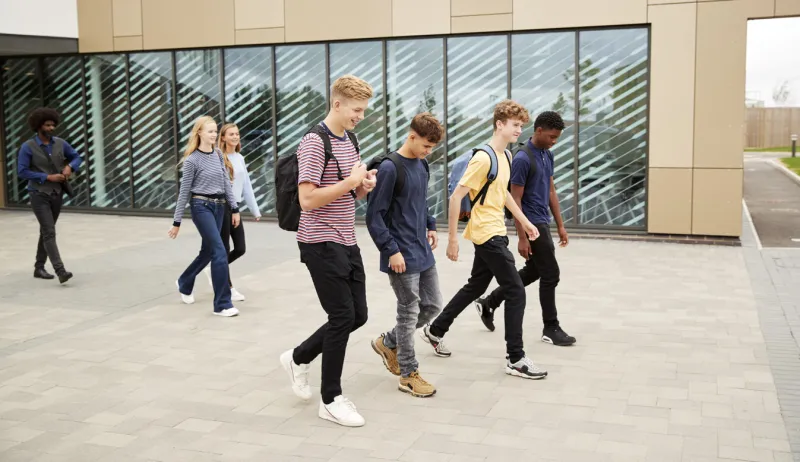 group of high school students walking out of college building together
