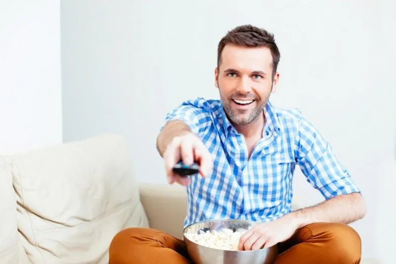 bel homme heureux tenant une télécommande