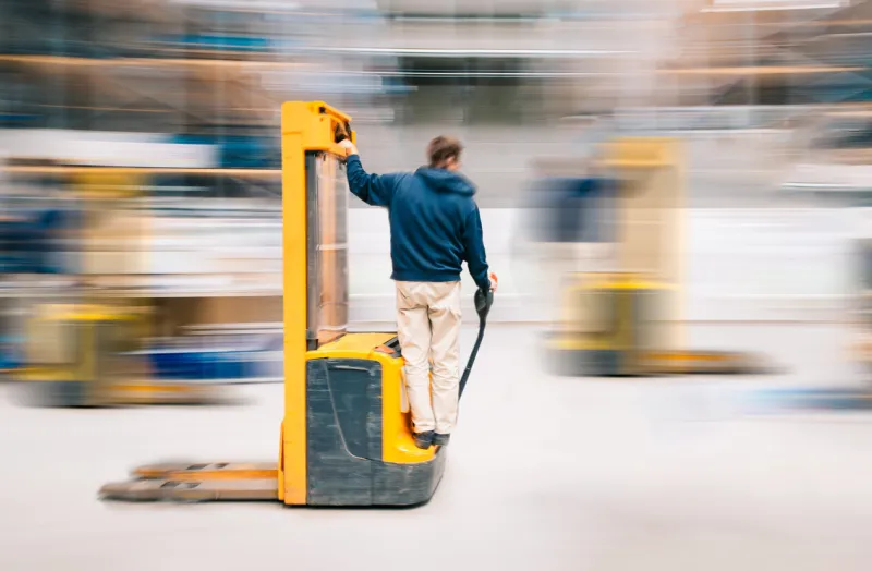 forklift worker in motion at work in warehouse , long exposure blurred
