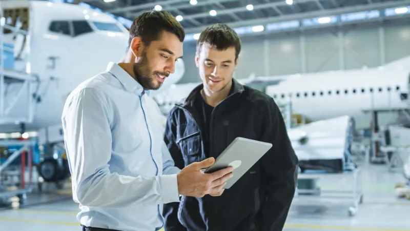 aircraft maintenance worker and engineer having conversation holding tablet