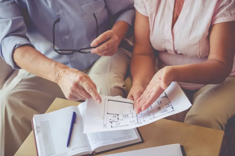 cropped image of beautiful old man and woman discussing house project while sitting on couch at home