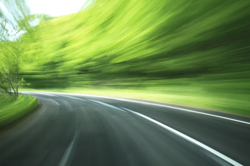 road in motion blur at green forest