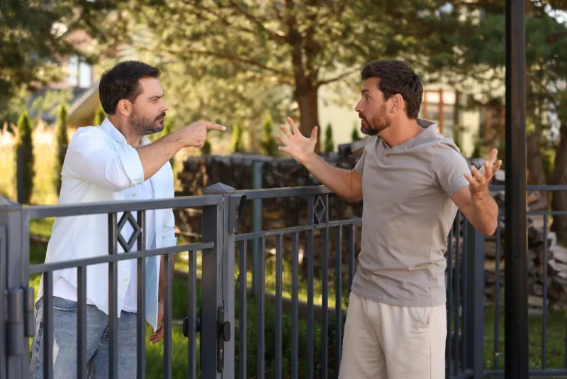angry neighbours having argument near fence outdoors
