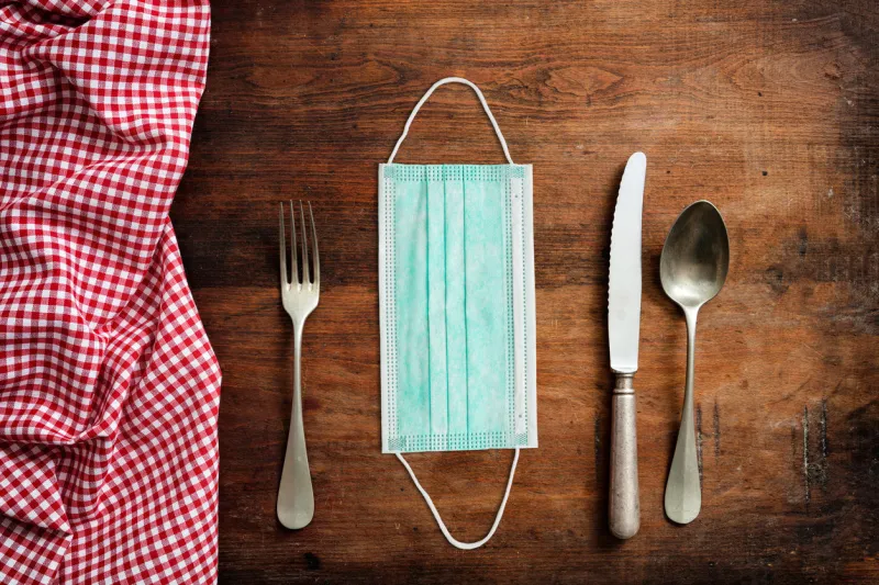 coronavirus for food and restaurant concept face protective mask and table setting on wooden table background covid spread prevention measure, template