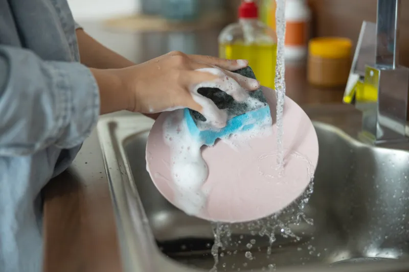 close up of female hands cleaning a dirty plate