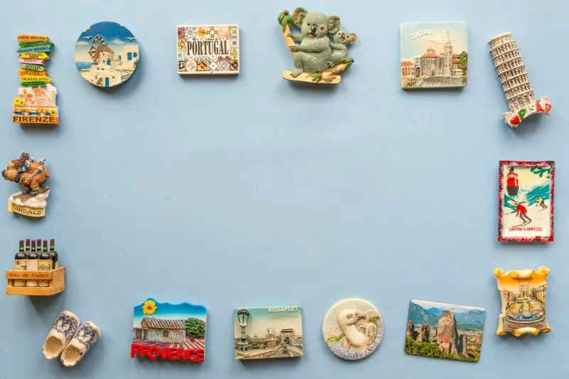 various souvenir magnets from several world country arranged on the blue background