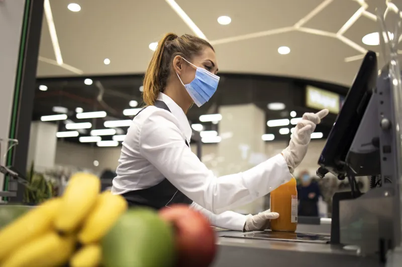 cashier with protective hygienic mask and gloves working in supermarket and fighting against covid-19 or corona virus pandemic