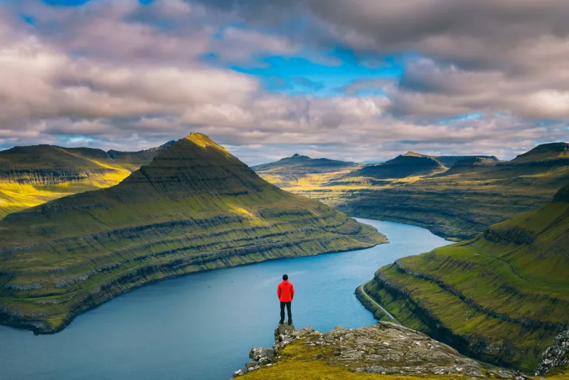 hiker enjoys spectacular views over fjords from the summit of a mountain near funningur on faroe islands