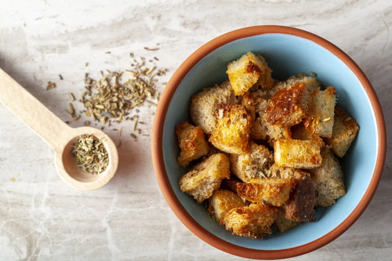 close up flat lay image of home made croutons in a bowl bread cubes were baked to crisp in oven and dipped into olive oil or butter and finished with italian seasoning used as a versatile garnish
