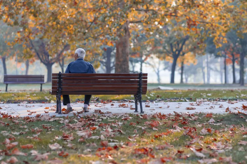 lonely senior old man sitting on bench in park