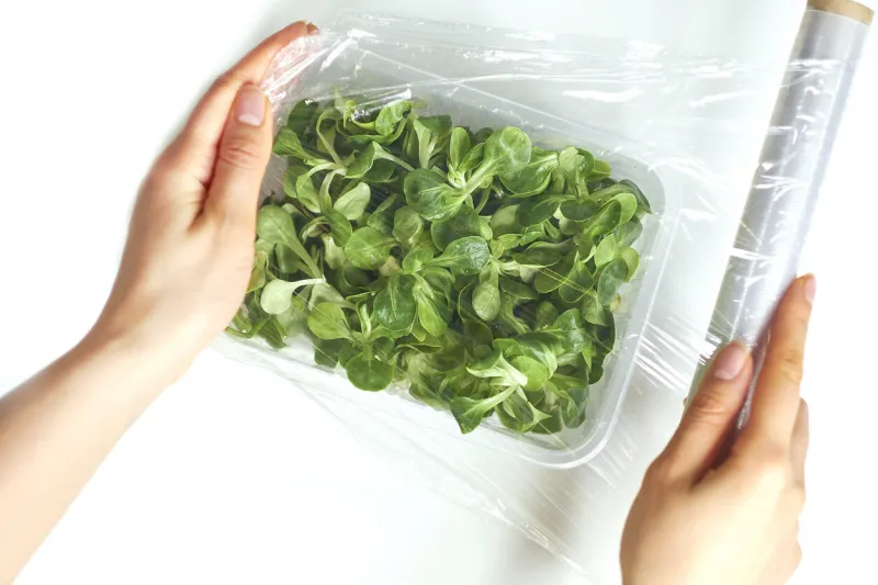 woman using food film for food storage on a white table roll of transparent polyethylene food film for packing products