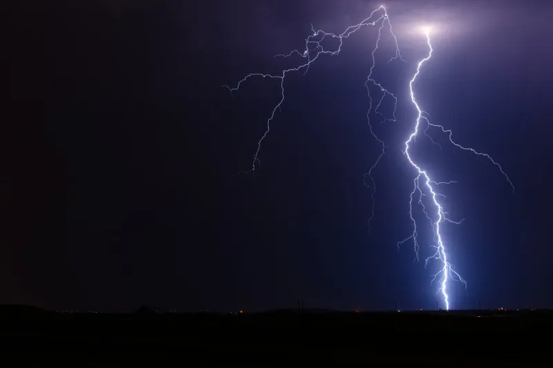 thunderstorm lightning bolt strike from a strong storm at night with a dark sky background
