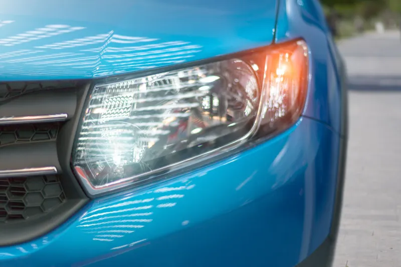 blue modern car closeup of headlight exterior detail, shallow depth of field