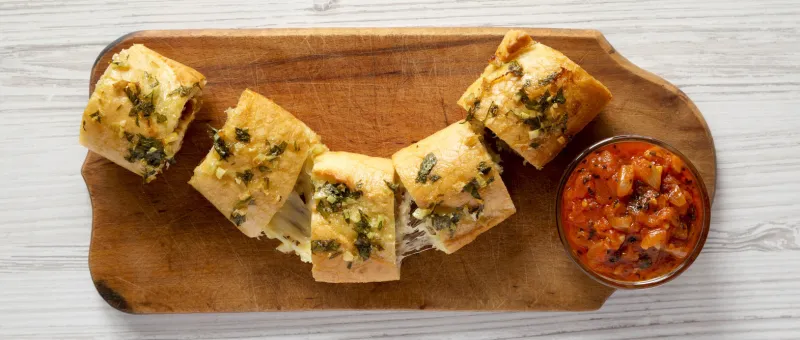 homemade chicken parmesan-stuffed garlic bread on a rustic wooden board on a white wooden background, top view overhead, from above, flat lay