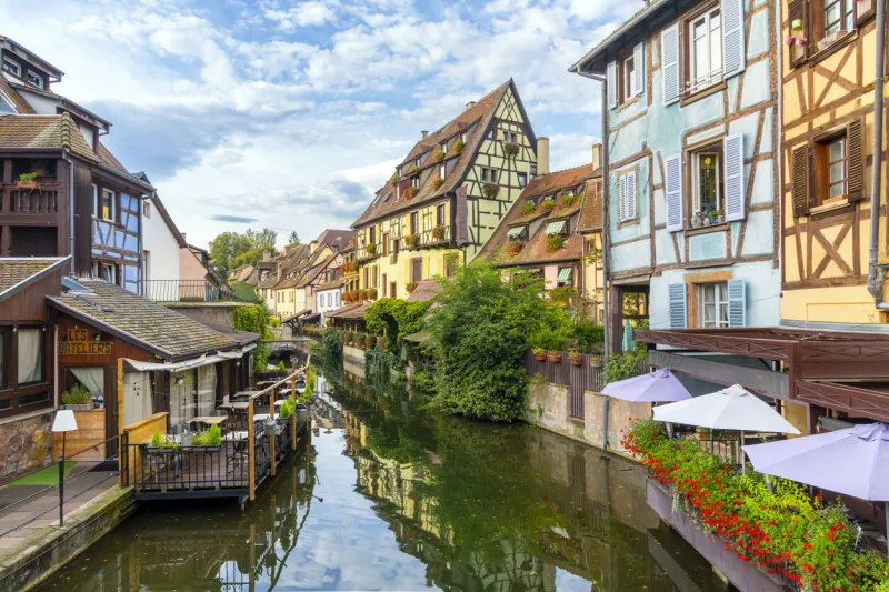 picturesque half timber buildings with waterfront cafes along the canal and lauch river in the medieval historic center of colmar, france, in the alsace region