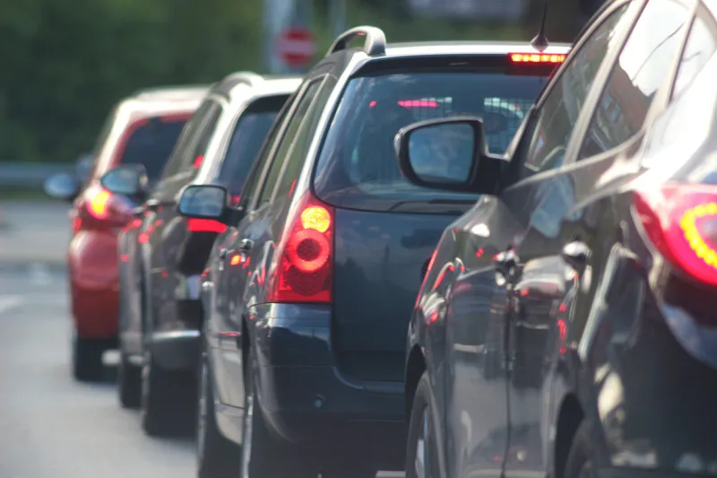 cars stopping in front of a red traffic light, with red lighted brake lights