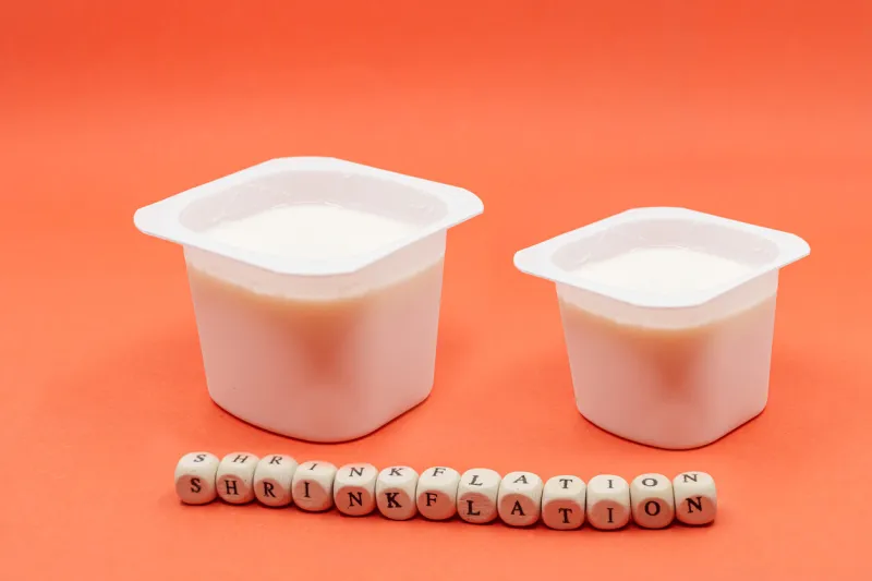 reduced yogurt on an orange background inflation, skimpflation or shrinkflation concept of less for the same price