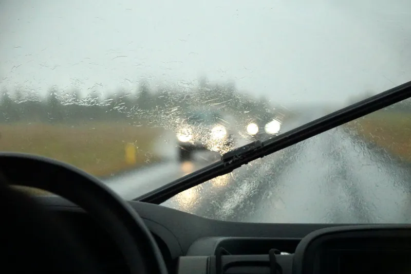 driving a car in the rain with activated windshield wipers, traffic