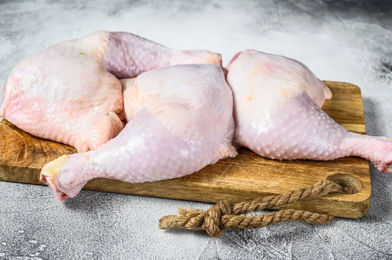raw chicken thighs on a chopping board gray background top view