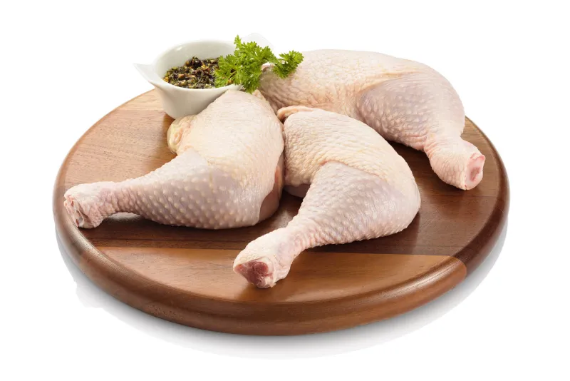 primal cut of raw chicken legs, with chicken thighs and drumsticks, on a wooden cutting board isolated on white background