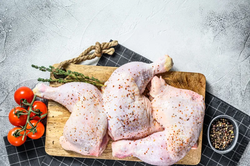 fresh raw chicken thighs, legs on a cutting board with spices, cooking gray background top view copy space