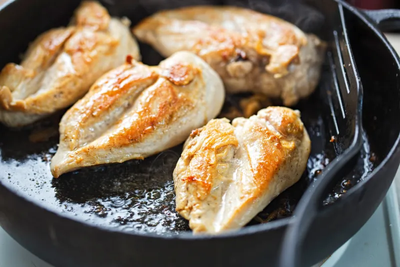 fried chicken breasts on vegetable oil, iron cast pan