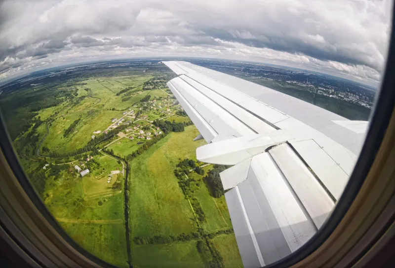 vue depuis la fenêtre de l'avion sur les champs verts et les nuages