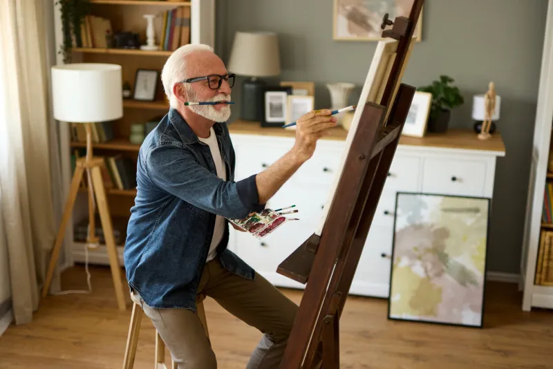 elderly man painting on a canvas at home