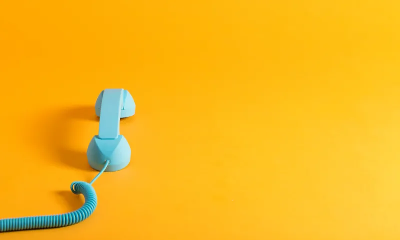 vintage style blue telephone handset on a yellow background