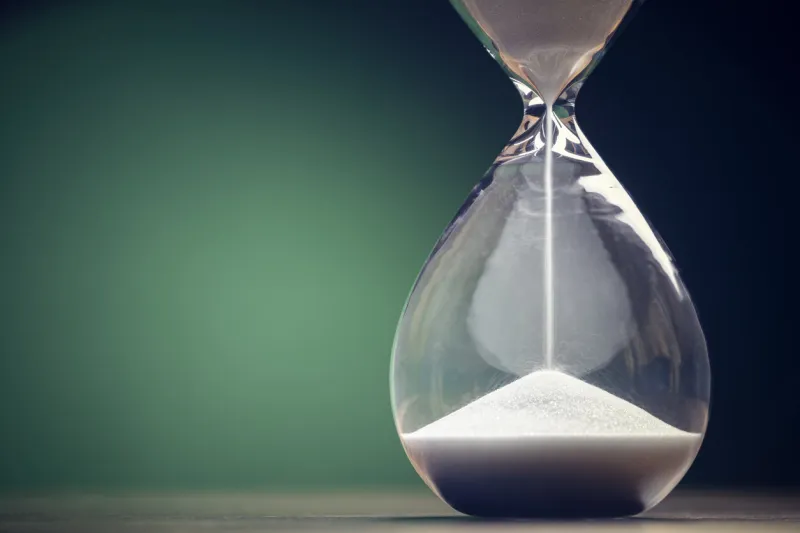 hourglass time passing green background concept for business deadline, urgency and running out of time