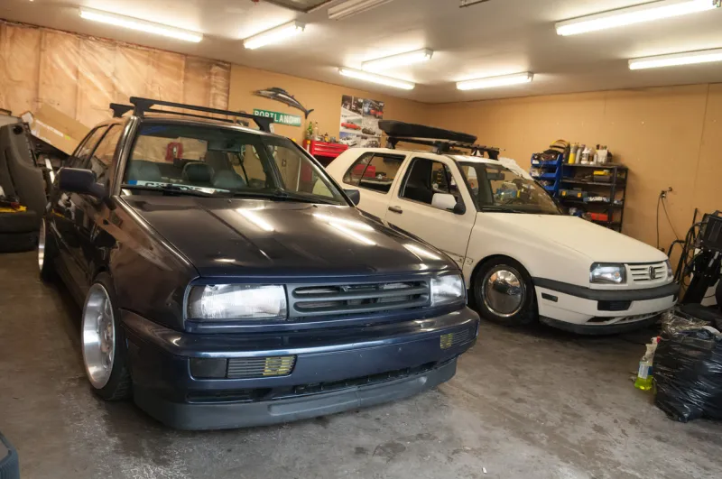 dartmouth, canada - march 12, 2011  lowered and heavily modified mk3 volkswagen jetta sedan and mk3 golf hatchback parked inside a garage