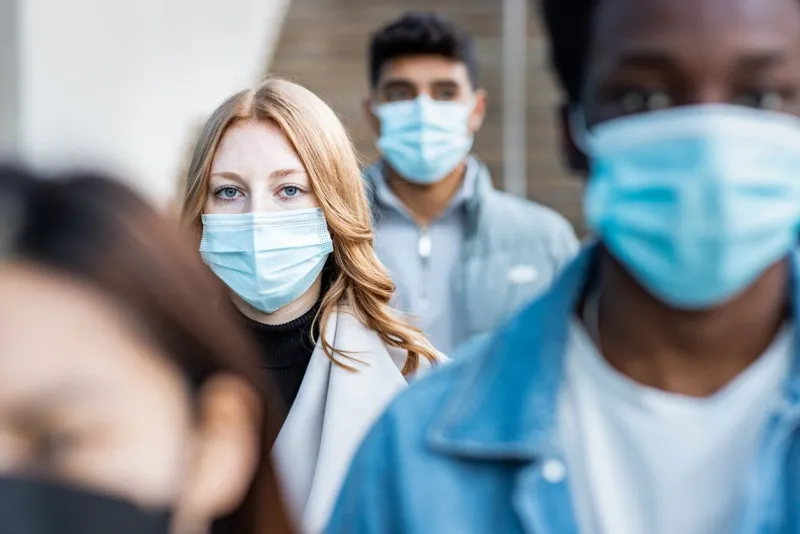 authentic shot of multiracial people in the city wearing face mask and walking on the pavement commuting to work - lifestyle and health issues concepts