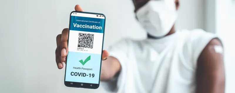 african american teenager shows vaccine passport on mobile phone to validate travel permission by the digital document