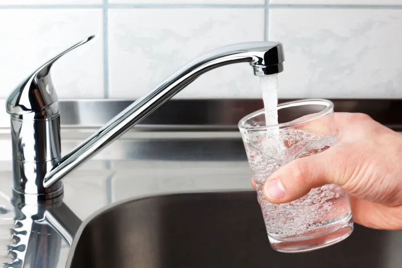 hand holding a glass of water poured from the kitchen faucet