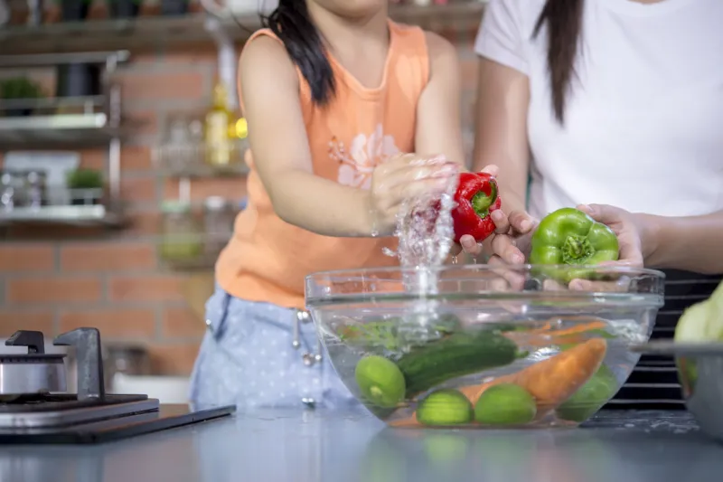 hands washing fresh vegetables paprika red, green, yellow, in glass bowl