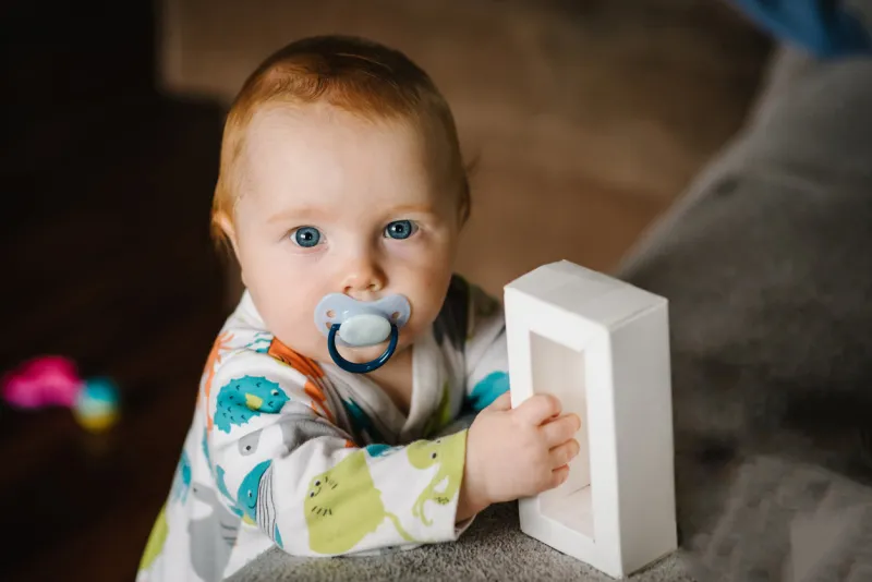 the infant is playing with toys funny baby boy standing in nursery room at home baby health care and family concept