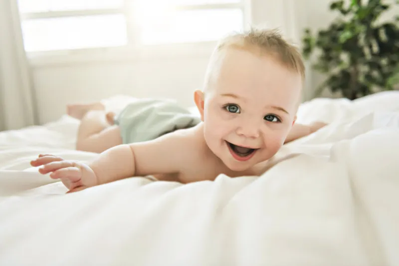 a cute baby boy lying on a white bed