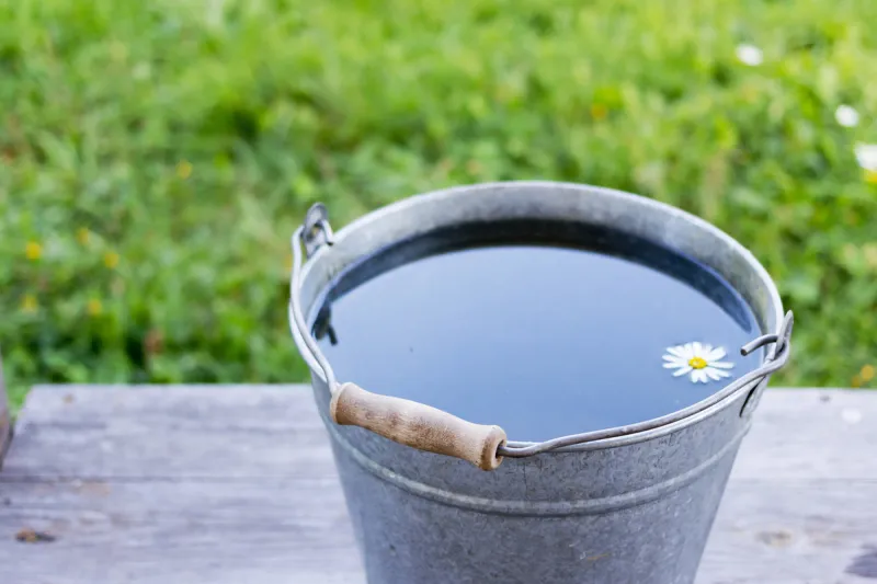metal bucket with water that is standing on the wooden boards outdoors