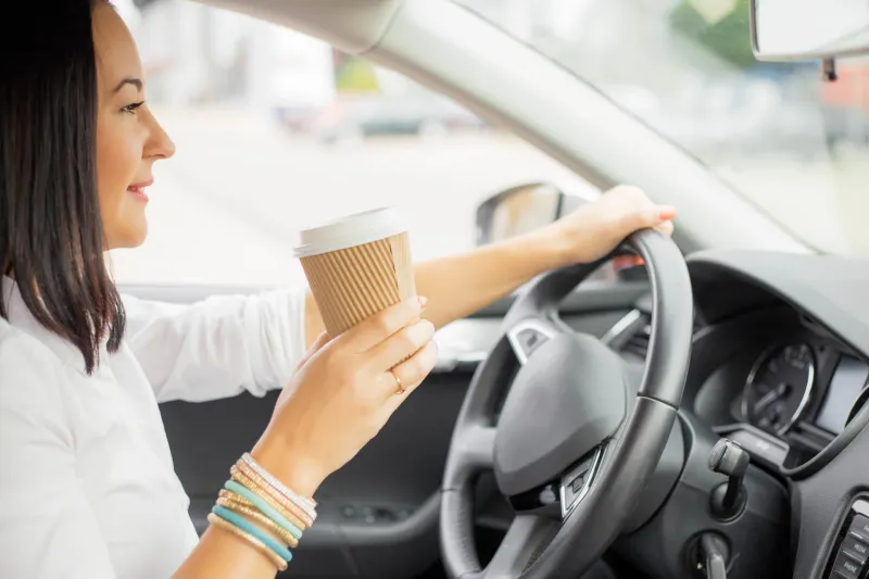 woman driving and holding a coffee cup
