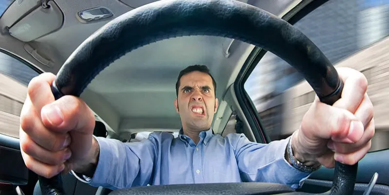 a furious man driving, as seen from behind the wheel shot using a very wide fisheye lens focused on the driver's face