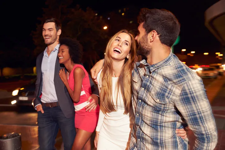 four friends walking through town together at night