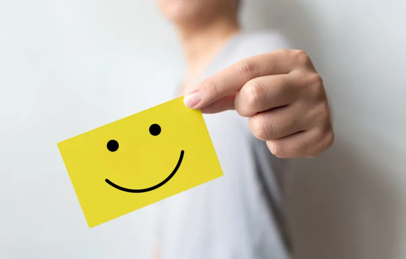 customer service experience and business satisfaction survey man holding yellow card with smiley face