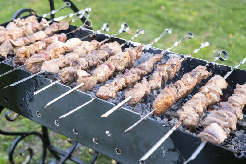 barbecue on the grill close-up, a lot of skewers with meat on the grill, background image, selective focus tinted image