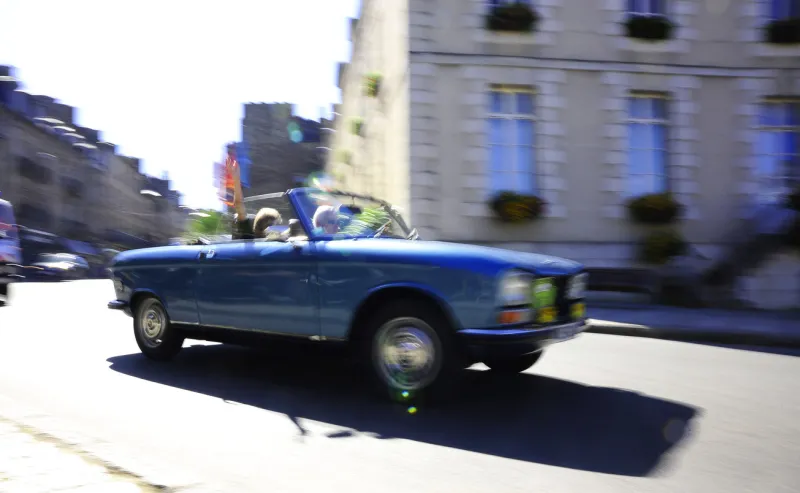 vintage car rally, brittany, france blue peugeot 205 convertible with person waving